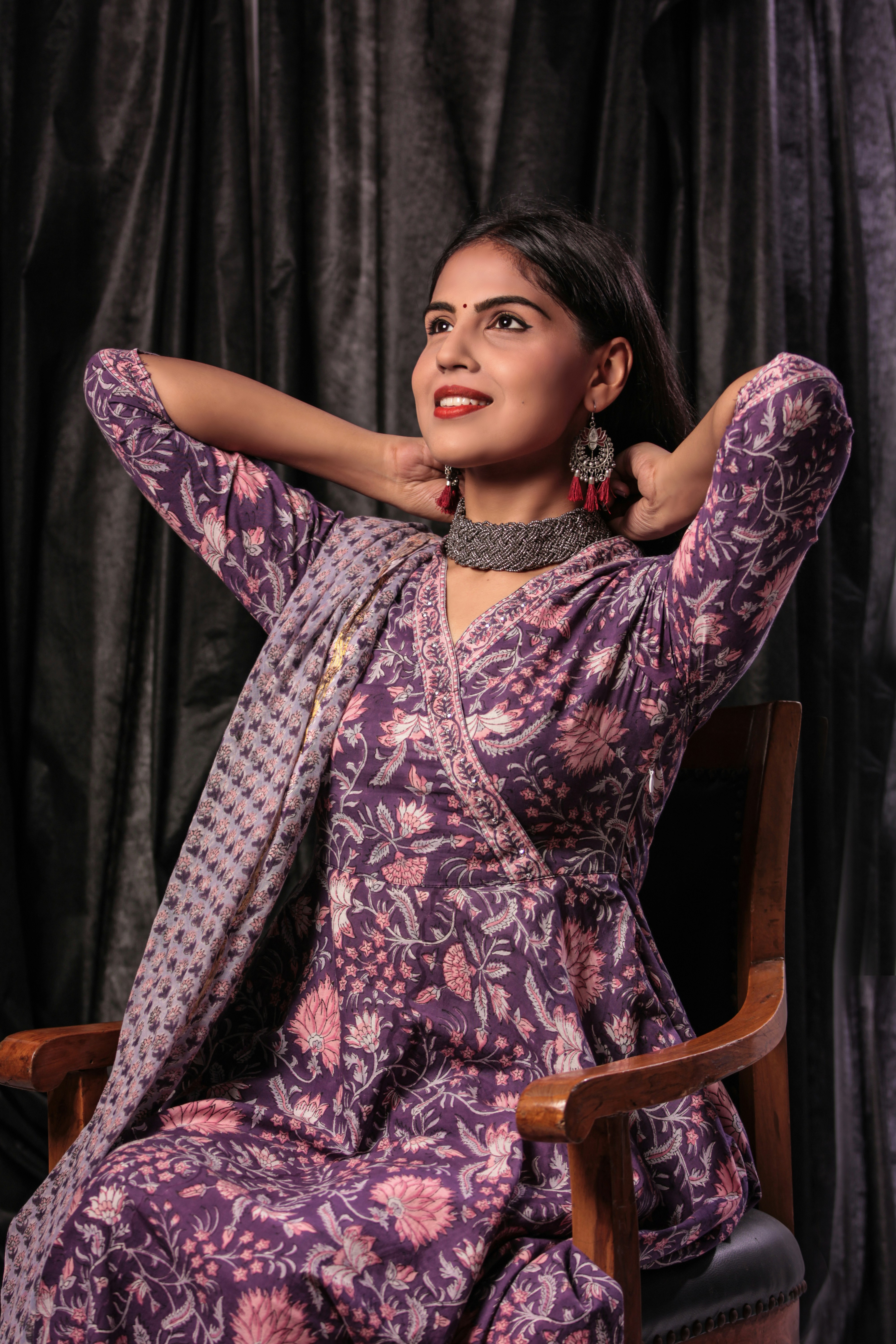 woman in pink and white floral dress sitting on brown wooden chair