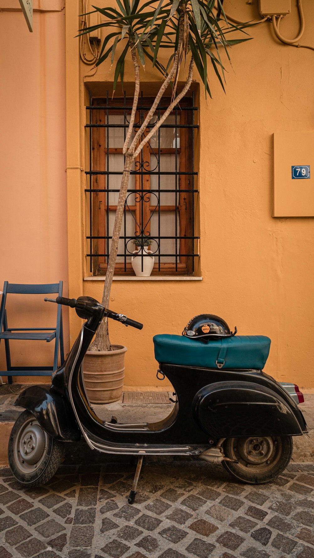 black and green motor scooter parked beside brown concrete wall