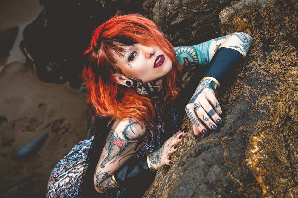 woman in black and white long sleeve shirt lying on brown rock