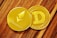 Two shiny cryptocurrency coins, one labeled Ethereum with its logo and the other labeled Dogecoin with its 'D' logo. They rest on a wooden surface.