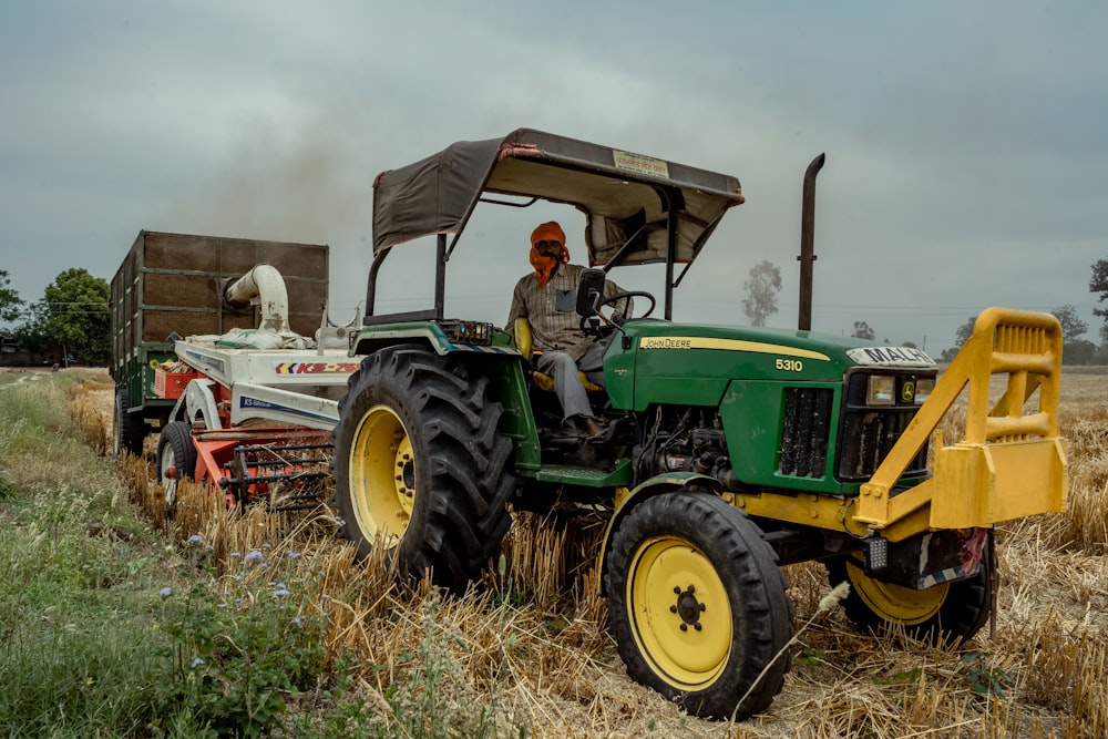 green and yellow tractor on brown grass field under gray sky during daytime