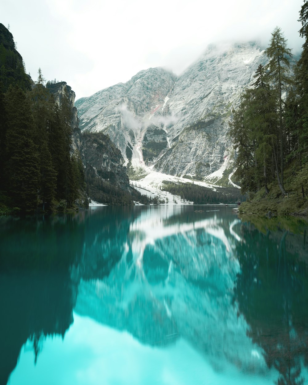 green lake surrounded by green trees and mountains during daytime