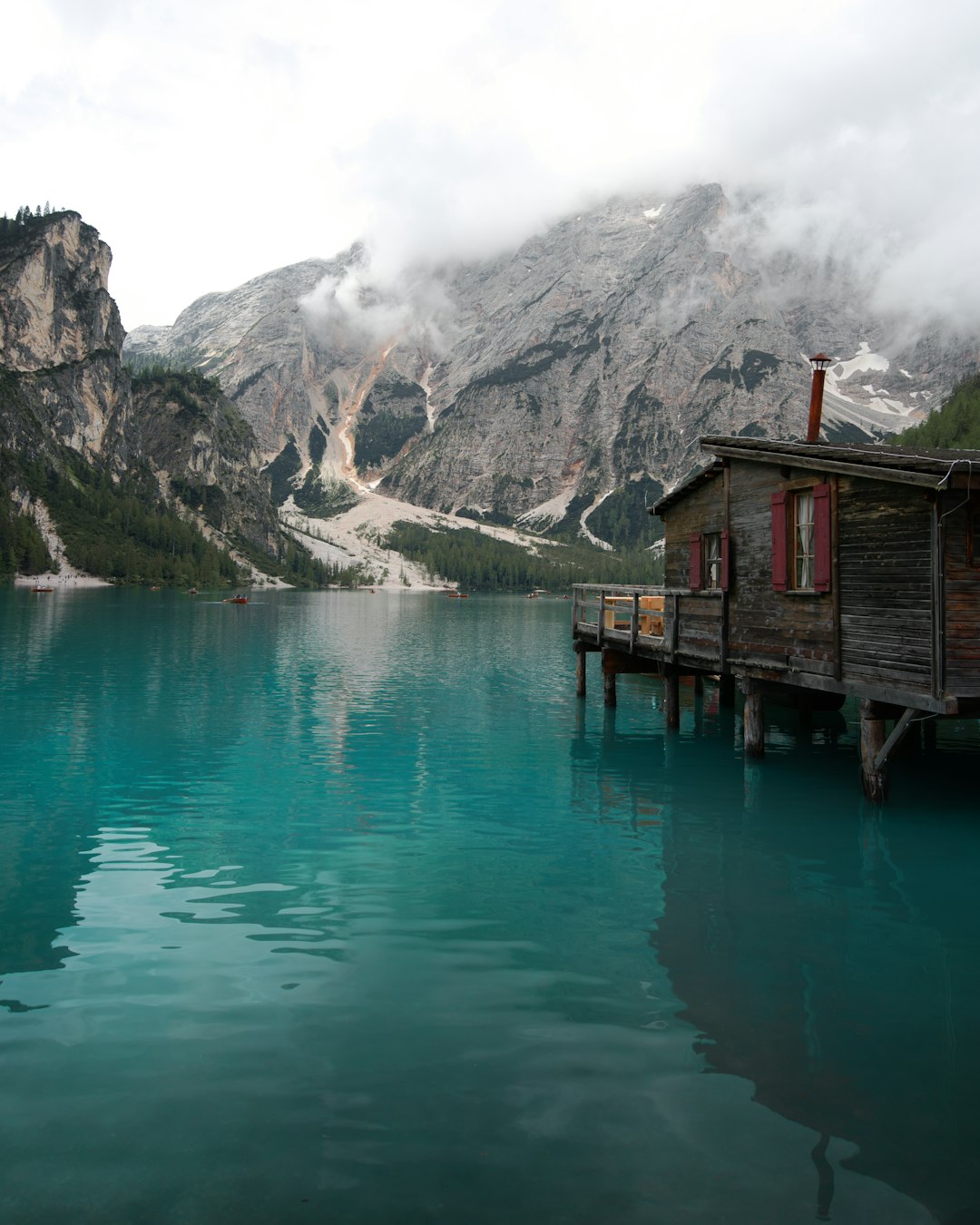 brown wooden house on lake near mountain during daytime