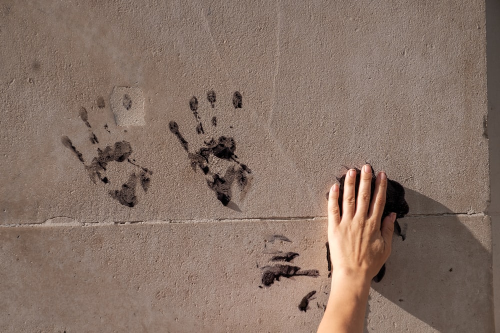 persons hand on gray concrete wall with black and white paint