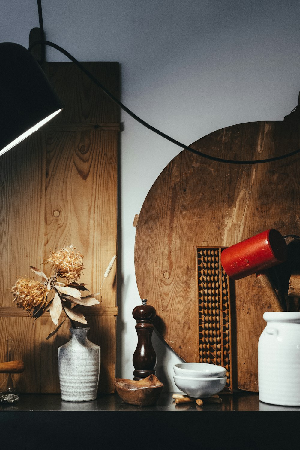 rote Keramiktasse neben schwarzer und brauner Keramikflasche auf braunem Holztisch