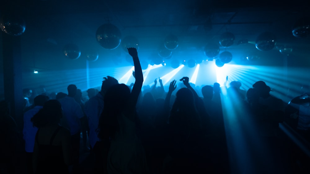 silhouette of people standing in front of stage with lights