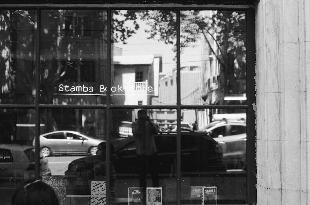 grayscale photo of man standing in front of store