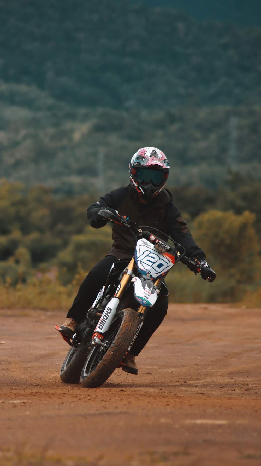 homem em jaqueta preta andando em laranja e branco motocross dirt bike