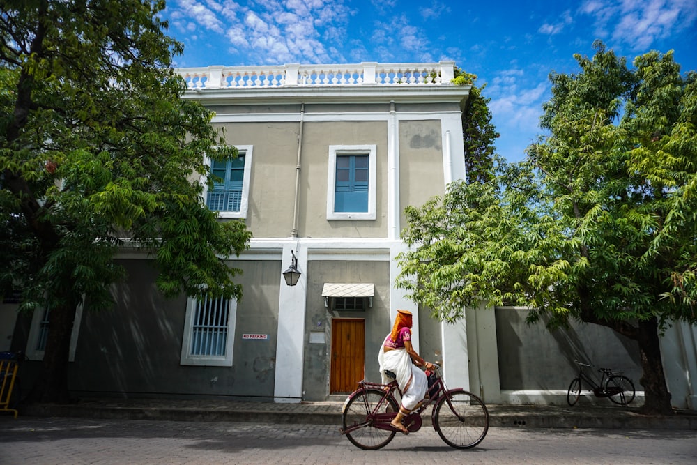 man in white shirt riding on bicycle near white concrete building during daytime