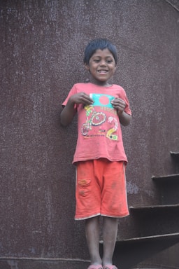 A cheerful child holding a colorful drawing of a car.