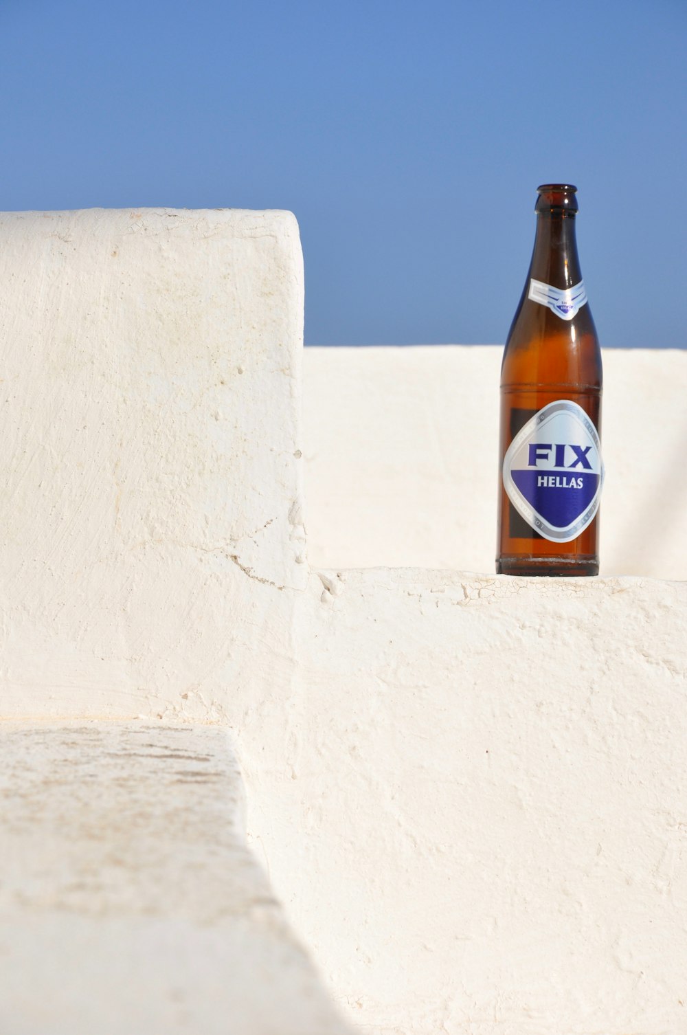 brown glass bottle on white concrete wall