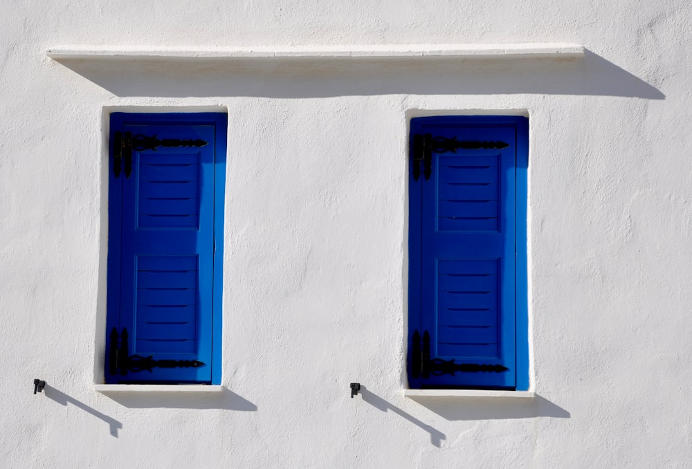 Fenêtre en bois bleu sur mur en béton blanc