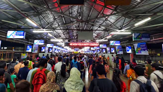 Wide shot of a busy platform with multiple LED advertisements in Kolkata.