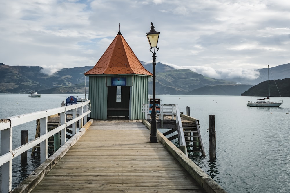 Muelle de madera marrón cerca del cuerpo de agua bajo el cielo nublado durante el día