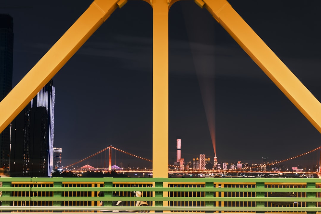 yellow metal bridge across city buildings during night time