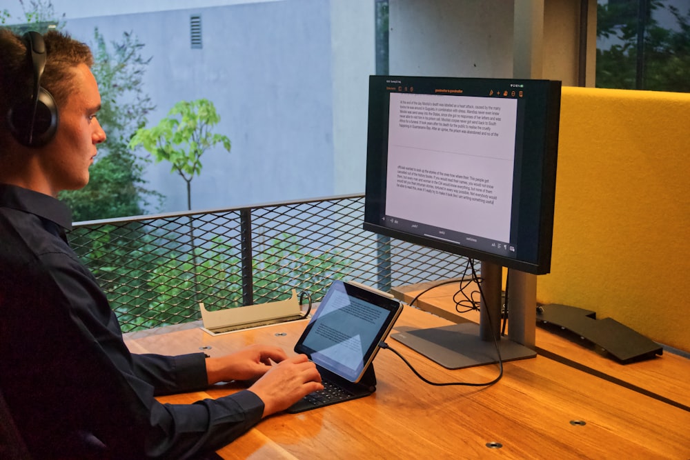 Personne en chemise noire à manches longues utilisant MacBook Pro sur une table en bois marron