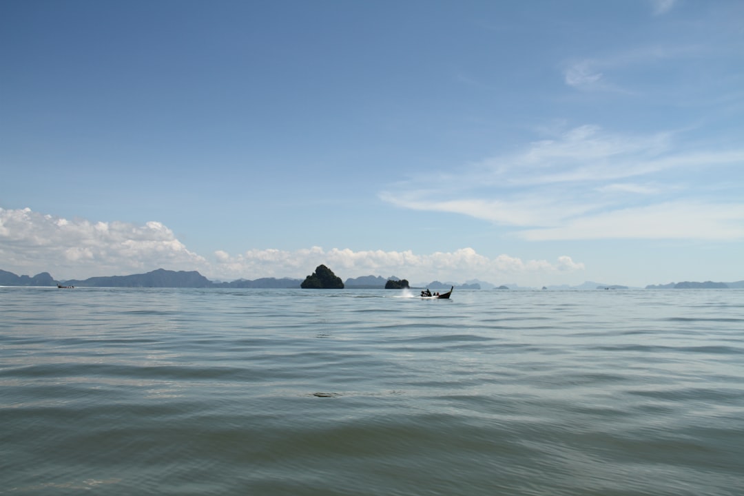 black rock formation on sea under blue sky during daytime