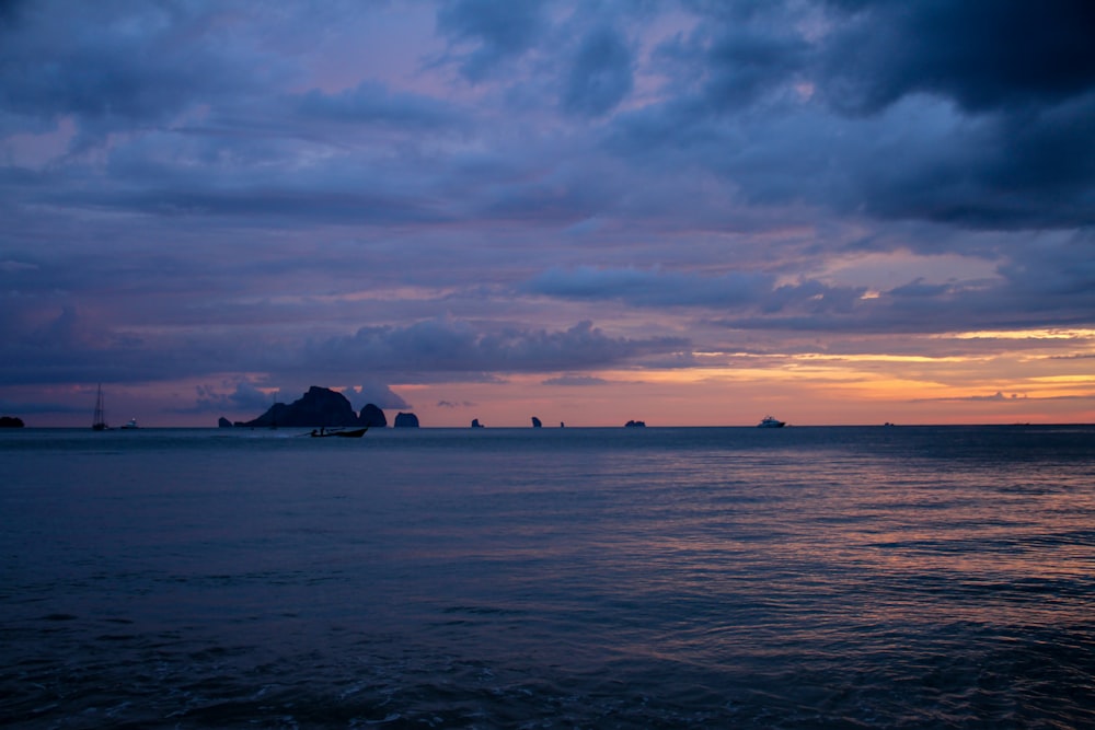 silhouette of mountain near body of water during sunset