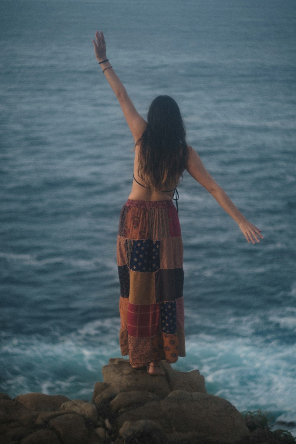 Mujer en vestido rojo y negro de pie en la playa durante el día