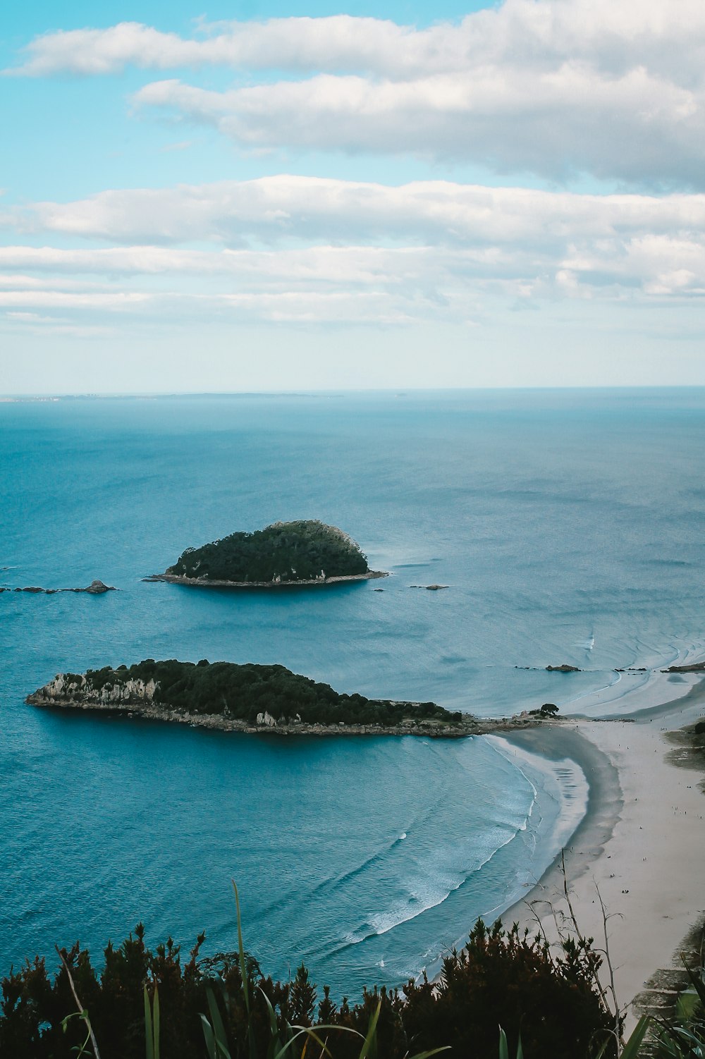 green island on blue sea under white clouds and blue sky during daytime