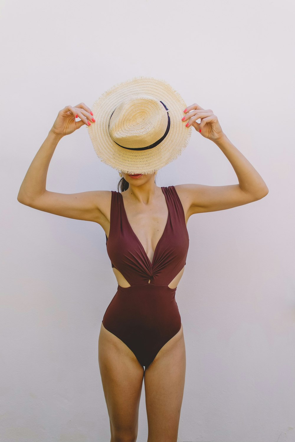 woman in brown one piece swimsuit wearing brown sun hat
