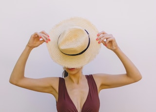 woman in brown one piece swimsuit wearing brown sun hat