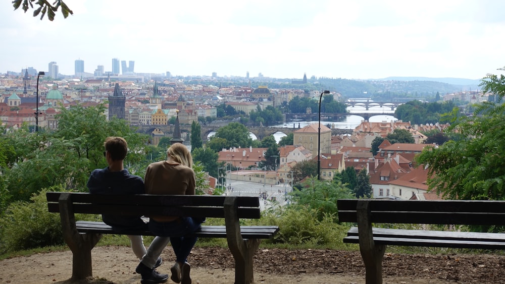 man and woman sitting on brown wooden bench during daytime