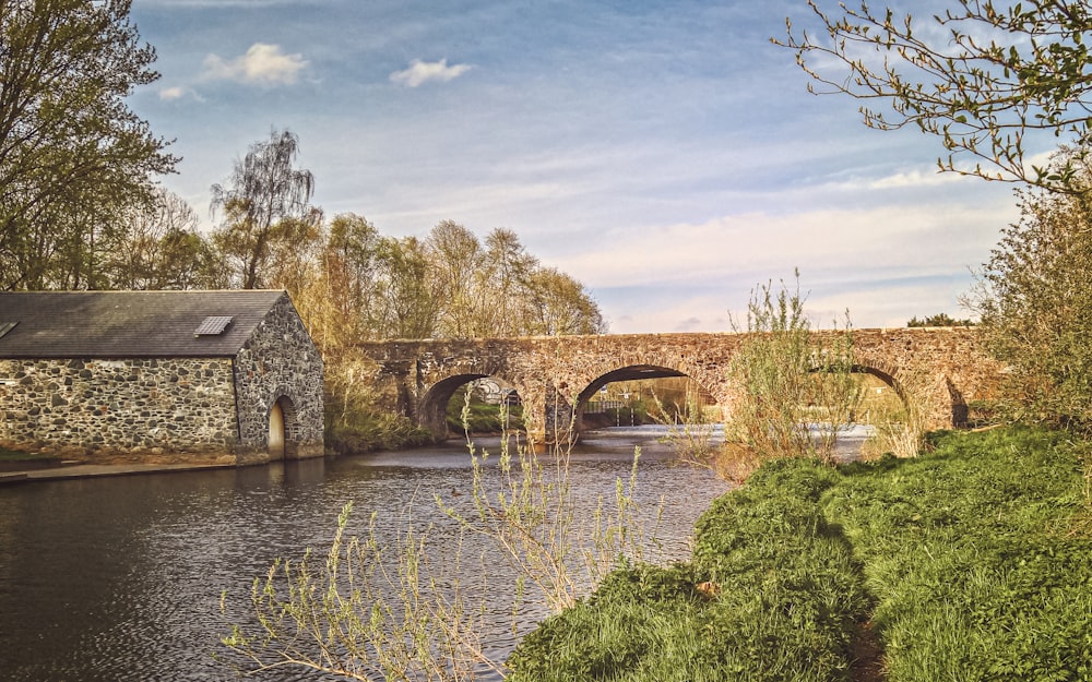 brown concrete bridge over river under white clouds and blue sky during daytime