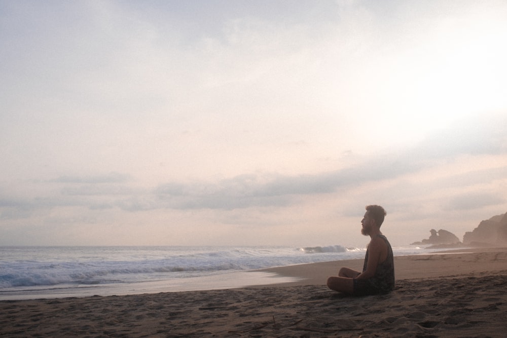 woman sitting on beach during daytime