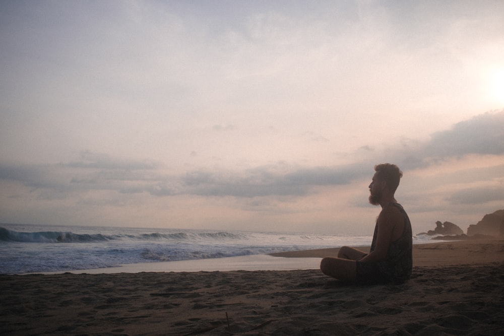 woman sitting on beach during sunset