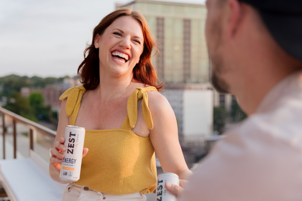 woman in yellow tank top holding white plastic cup