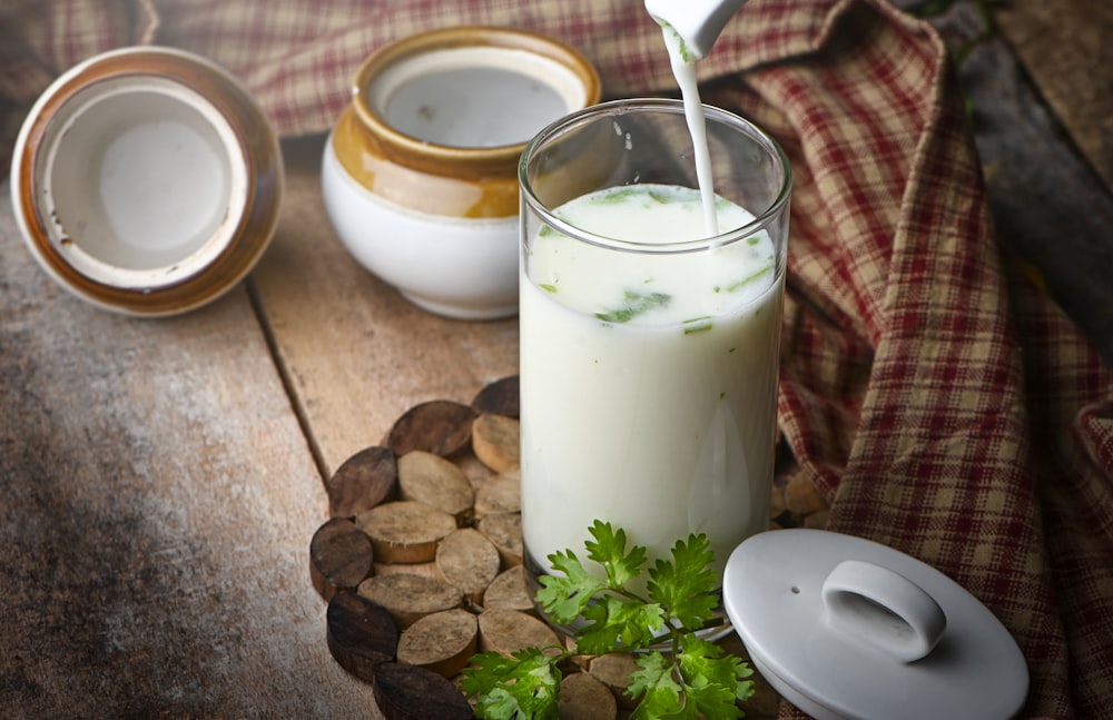 milk in clear drinking glass with green leaves and white cream