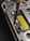 A close-up view of the inside of an electronic device, possibly a smartphone or a handheld gadget. The image focuses on a circuit board with small components, wires, and a yellow barcode sticker. A screwdriver is visible engaging with a screw, suggesting a repair or assembly process.