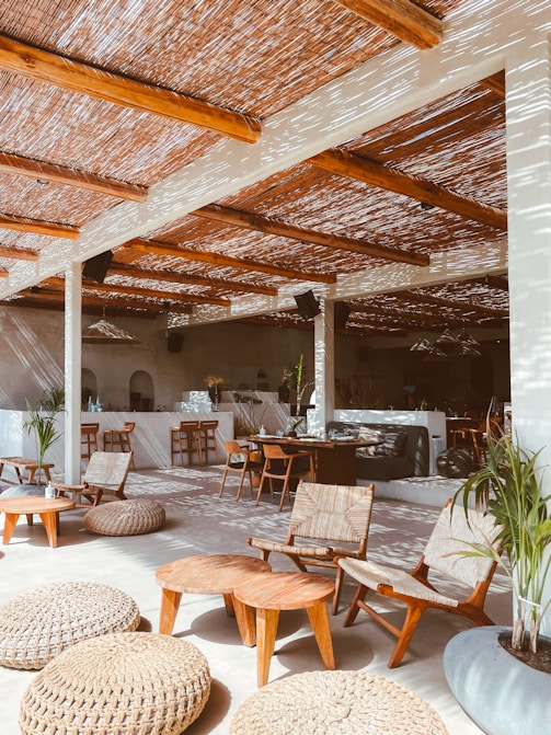 une terrasse ombragée avec du mobilier en bois, des plantes vertes et des murs blancs