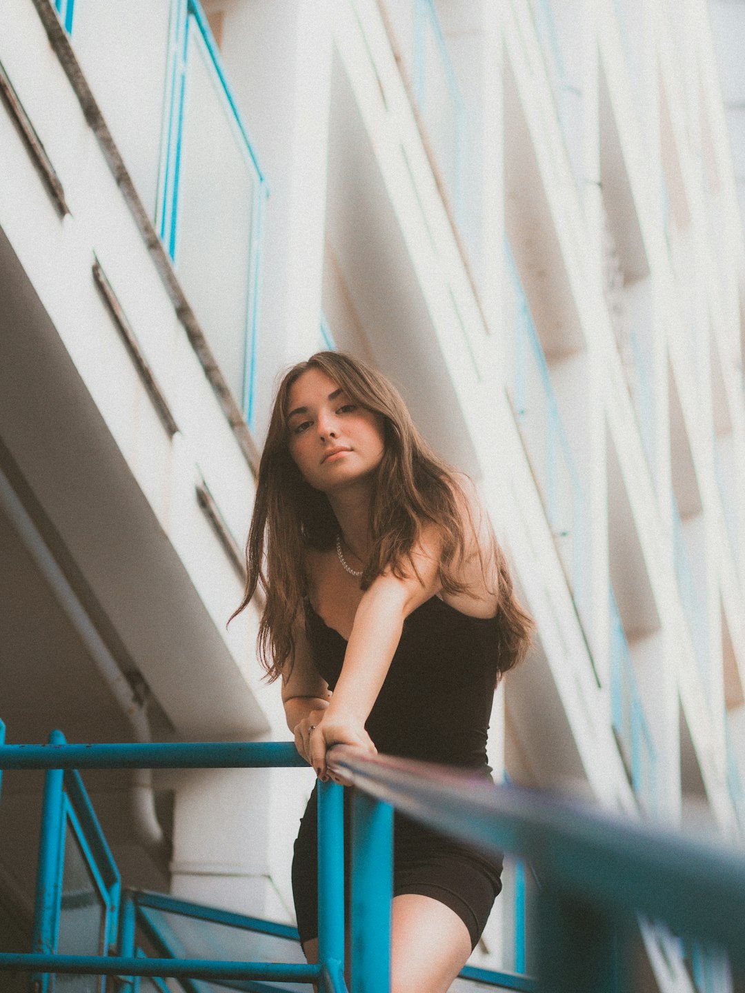 woman in black tank top leaning on white wall