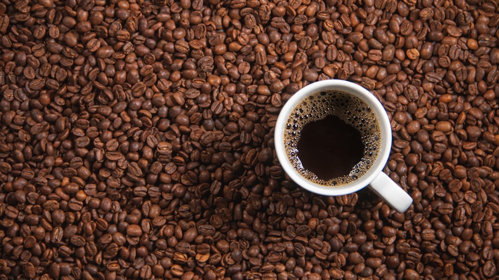 茶色のコーヒー豆に白いセラミックマグカップ