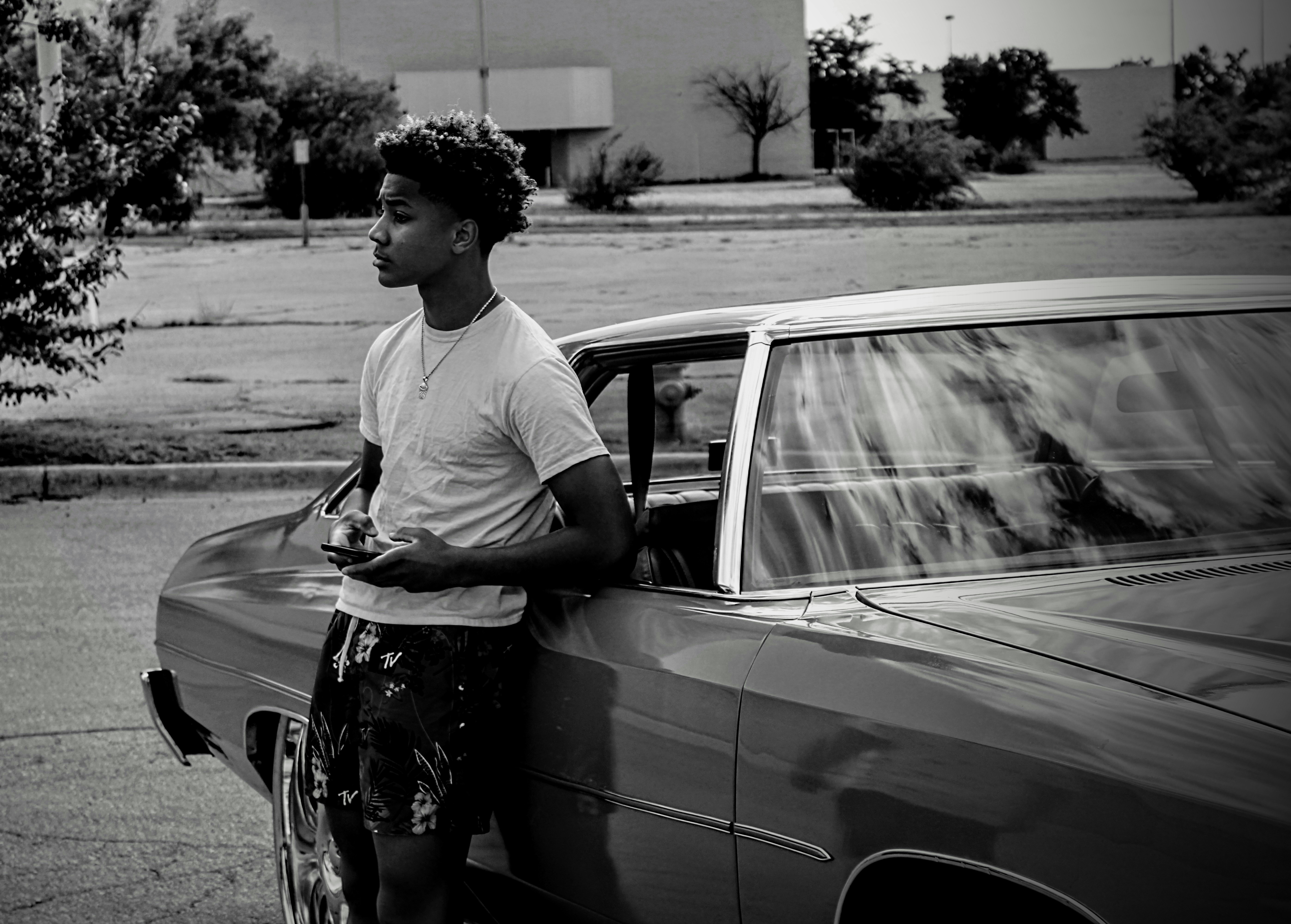 man in white crew neck t-shirt standing beside car