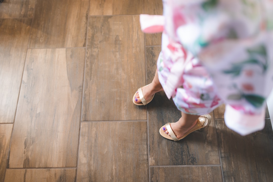 person in white and pink floral skirt standing on brown wooden floor