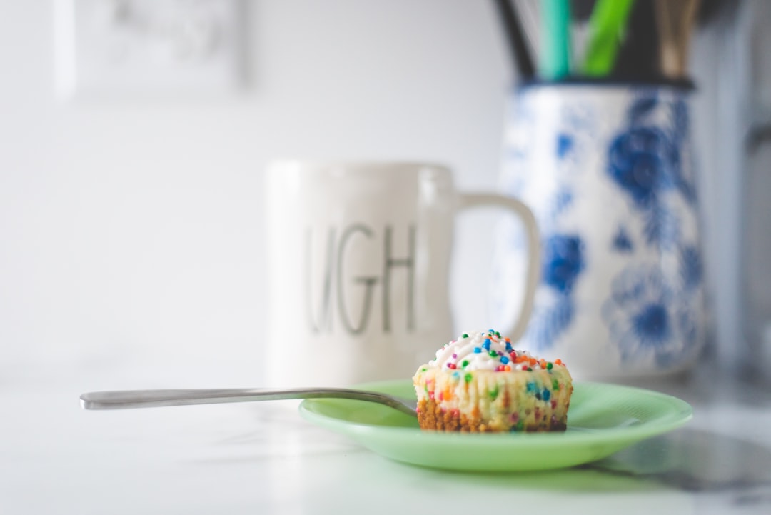 white ceramic mug beside white and blue floral ceramic plate with cupcake