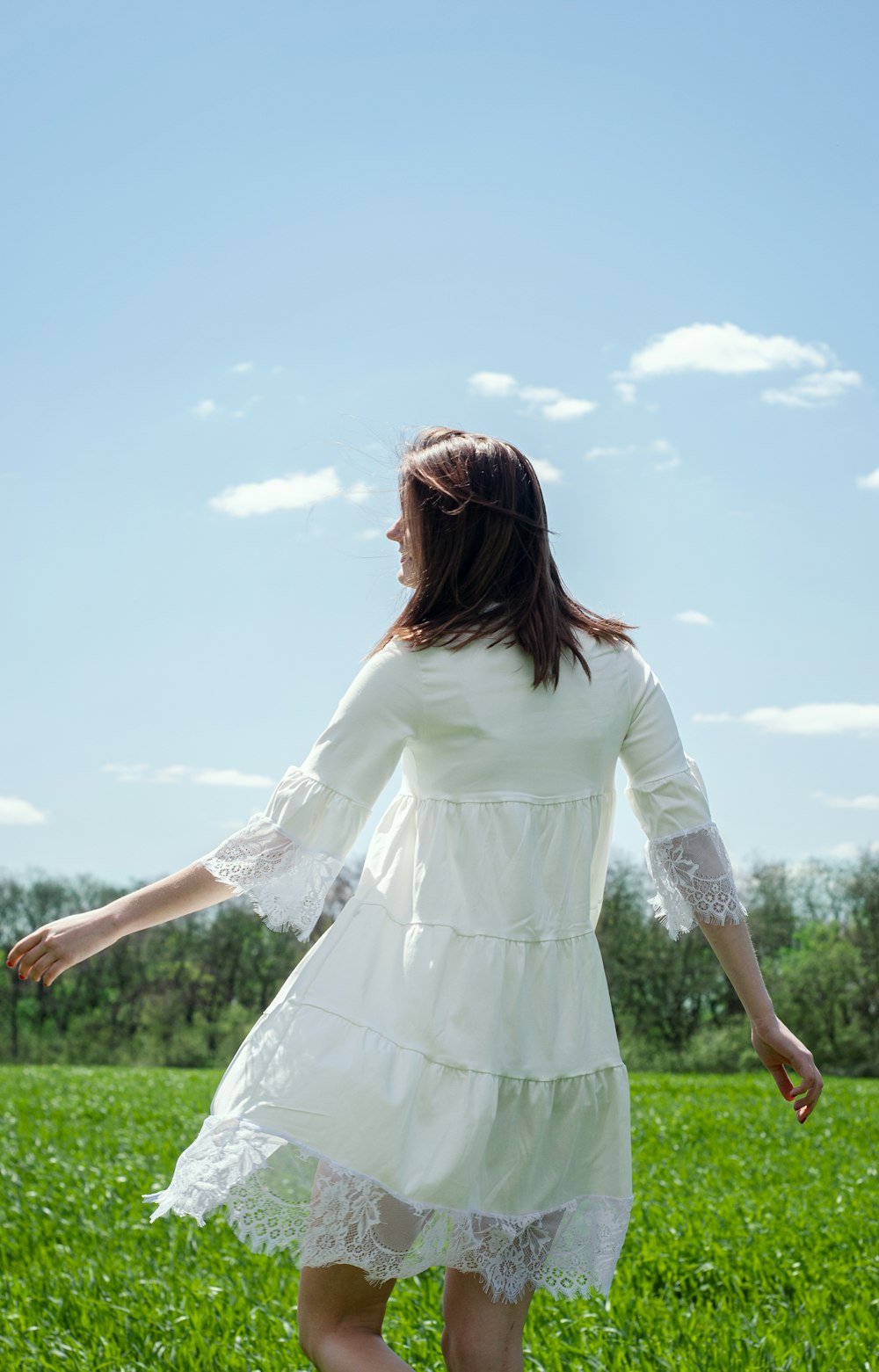 woman in white long sleeve dress standing on green grass field during daytime