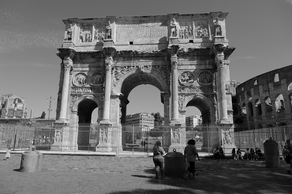 grayscale photo of people walking on arch gate