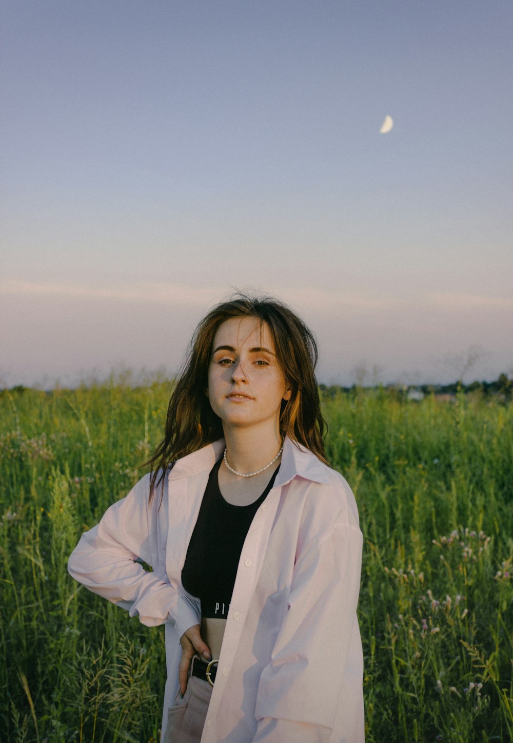 woman in white jacket standing on green grass field during daytime