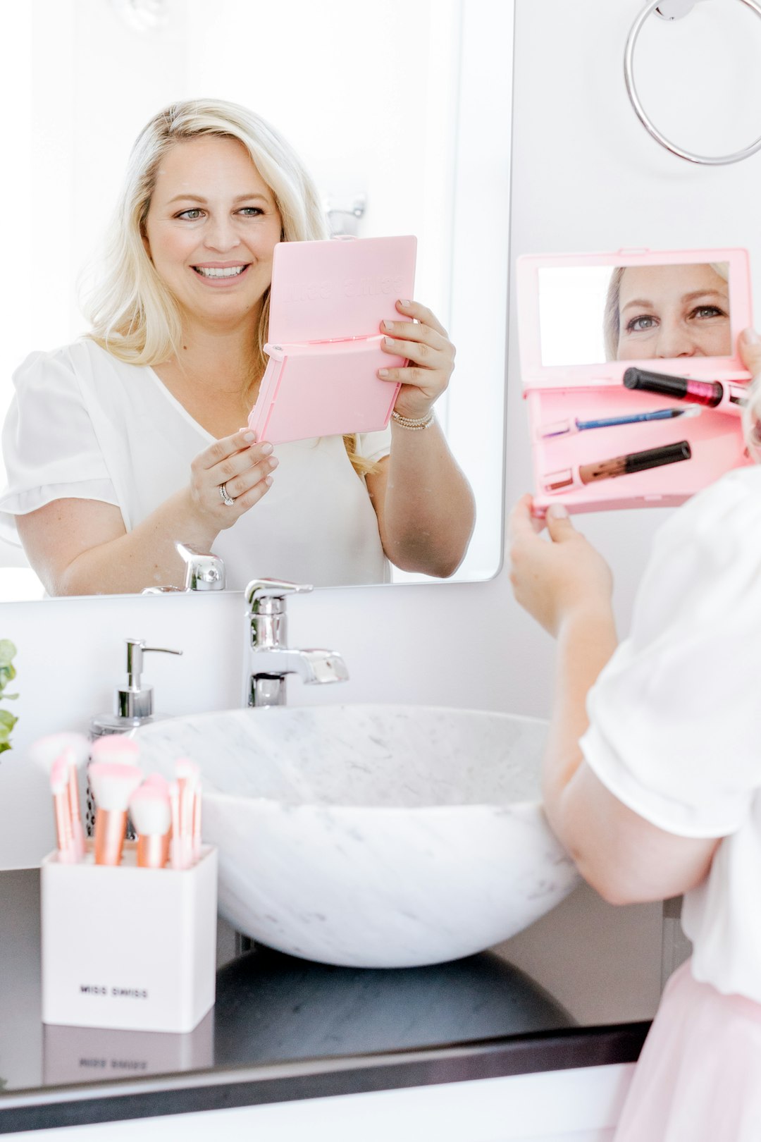 woman in white crew neck t-shirt holding pink book