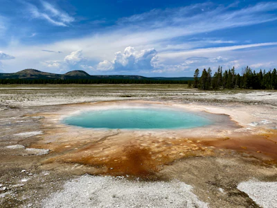 A hot spring ringed with orange bacterial mats in a Yellowstone geyser basin