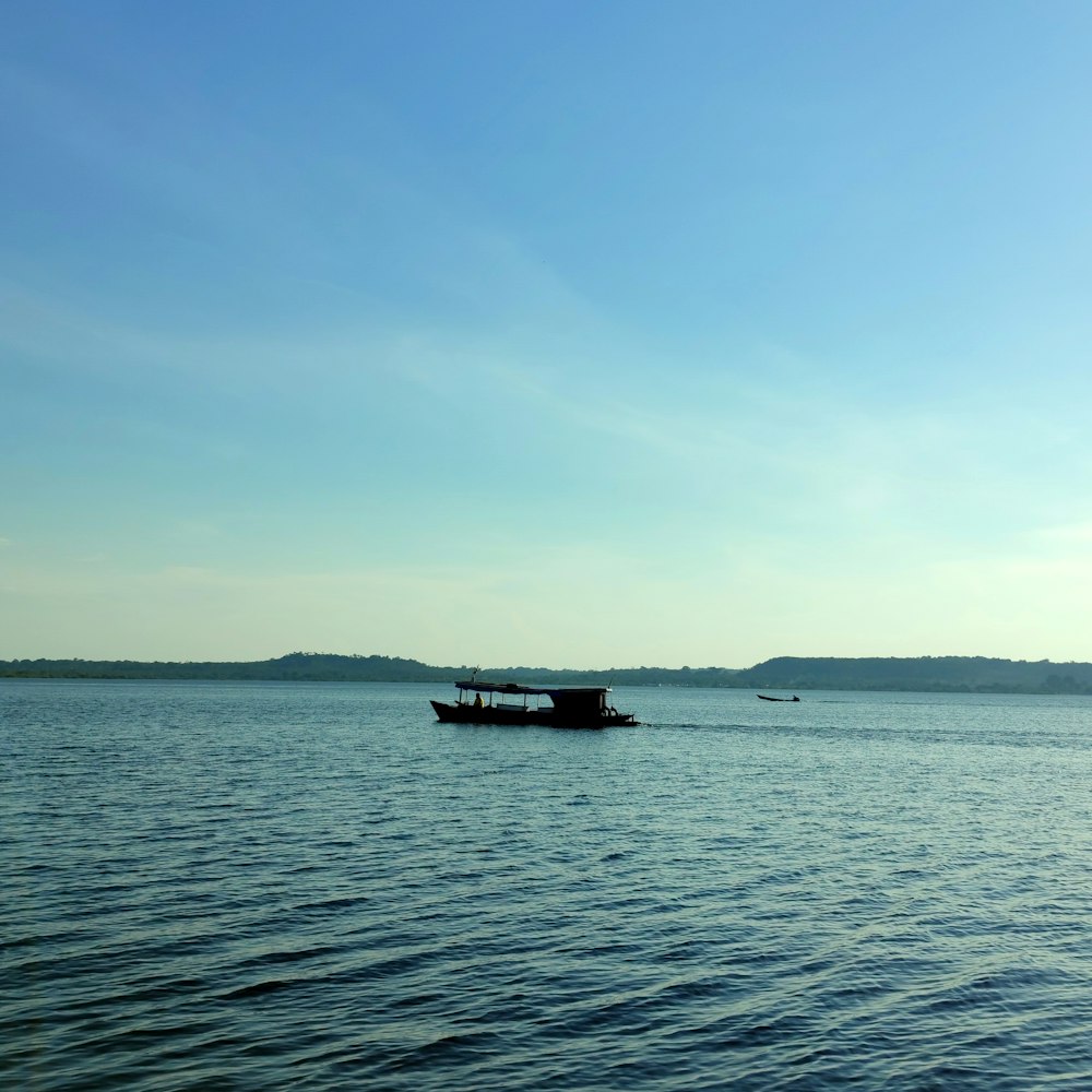 black boat on sea under blue sky during daytime