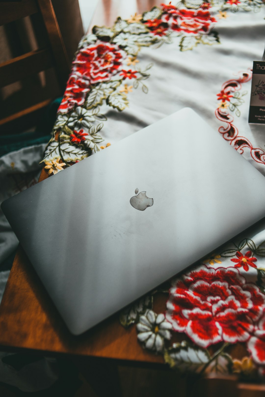 silver macbook on white and red floral textile