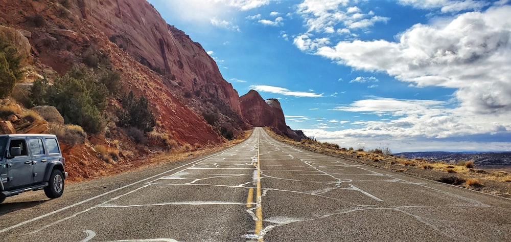 strada asfaltata grigia vicino a montagna marrone sotto il cielo blu durante il giorno