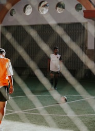 man in orange and white jersey shirt and black shorts standing on green and white tennis