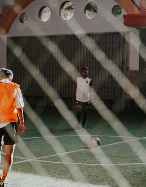 man in orange and white jersey shirt and black shorts standing on green and white tennis