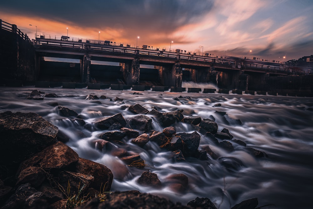 rocky river under bridge during night time